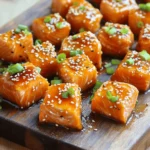 Für die Lachs-Bissen benötigst du: - 450 g Lachsfilet, ohne Haut und Gräten - 3 Esslöffel Honig - 2 Esslöffel Sriracha-Sauce (nach Geschmack anpassen) - 1 Esslöffel Sojasauce - 1 Esslöffel Limettensaft - 1 Teelöffel frisch geriebener Ingwer - 1 Knoblauchzehe, fein gehackt - Salz und schwarzer Pfeffer nach Geschmack Diese Zutaten bringen den perfekten Mix aus süß und scharf. Der Lachs bleibt saftig und zart. Für die Marinade mischst du Honig, Sriracha, Sojasauce, Limettensaft, Ingwer und Knoblauch. - Honig sorgt für Süße. - Sriracha fügt Schärfe hinzu. - Sojasauce gibt Umami. - Limettensaft bringt Frische. - Ingwer und Knoblauch verleihen Tiefe. Die Marinade ist einfach und voller Geschmack. Du kannst die Schärfe der Sriracha nach deinem Geschmack anpassen. Um die Lachs-Bissen noch besser zu machen, kannst du Sesamsamen und Frühlingszwiebeln verwenden. - Sesamsamen fügen Crunch hinzu. - Frühlingszwiebeln bieten Frische und Farbe. Serviere die Lachs-Bissen auf einem Bett aus Reis oder Quinoa. Du kannst auch Zahnstocher verwenden für eine einfache Vorspeise. Wenn du mehr Schärfe magst, träufle etwas extra Honig-Sriracha-Sauce darüber. Zuerst heizen Sie den Ofen auf 200°C vor. Das sorgt für eine gleichmäßige Hitze. Nehmen Sie ein Backblech und legen Sie es mit Backpapier aus. So bleibt alles sauber. Schneiden Sie das Lachsfilet in Würfel, etwa 2,5 cm groß. Legen Sie die Stücke in eine große Schüssel. In einer kleinen Schüssel mischen Sie die Marinade. Geben Sie 3 Esslöffel Honig, 2 Esslöffel Sriracha-Sauce, 1 Esslöffel Sojasauce, 1 Esslöffel Limettensaft, 1 Teelöffel frisch geriebenen Ingwer und 1 fein gehackte Knoblauchzehe hinein. Rühren Sie alles gut um. Gießen Sie die Mischung über die Lachswürfel. Tossieren Sie die Stücke sanft, bis sie gut überzogen sind. Lassen Sie den Lachs für 15-20 Minuten marinieren. So kann das Aroma gut einziehen. Nach dem Marinieren sind Sie bereit zum Backen. Verteilen Sie die Lachswürfel gleichmäßig auf dem Backblech. Streuen Sie etwas Salz und schwarzen Pfeffer darüber. Schieben Sie das Blech in den Ofen und backen Sie die Lachs-Bissen für 12-15 Minuten. Der Lachs sollte durchgegart sein und sich leicht mit einer Gabel zerteilen lassen. Sobald die Zeit um ist, nehmen Sie das Blech aus dem Ofen. Lassen Sie die Lachs-Bissen für einige Minuten ruhen. So bleiben sie saftig und zart. Jetzt kommt der spaßige Teil! Garnieren Sie die Lachs-Bissen mit Sesamsamen und gehackten Frühlingszwiebeln. Diese geben einen schönen Kontrast und frische Aromen. Servieren Sie die Lachs-Bissen mit Zahnstochern als leckere Vorspeise. Oder legen Sie sie auf ein Bett aus Reis oder Quinoa für ein Hauptgericht. Träufeln Sie etwas extra Honig-Sriracha-Sauce darüber für einen zusätzlichen Kick. Genießen Sie die Aromen! Um den besten Lachs zu kochen, sind einige Dinge wichtig. Achte darauf, frischen Lachs zu kaufen. Er sollte fest und glänzend sein. Schneide den Lachs in gleich große Stücke, etwa 2,5 cm. So garen sie gleichmäßig. Für das Backen verwende ein mit Backpapier ausgelegtes Blech. Das macht die Reinigung einfach und verhindert, dass der Lachs kleben bleibt. Sriracha gibt dem Lachs einen tollen Kick. Du kannst die Menge nach deinem Geschmack anpassen. Wenn du es milder magst, nimm weniger Sriracha. Du kannst auch etwas mehr Honig hinzufügen, um die Schärfe auszugleichen. Probiere es aus! Manche mögen es süßer, andere schärfer. Finde die perfekte Balance für dich. Lass den Lachs mindestens 15 bis 20 Minuten marinieren. So zieht die Sauce gut ein. Wenn du mehr Zeit hast, kannst du ihn auch länger marinieren. Achte darauf, dass die Marinade nicht zu dünnflüssig ist. Sie sollte schön am Lachs haften. Wenn die Sauce zu dick ist, kannst du etwas Wasser oder Limettensaft hinzufügen. So bekommst du die richtige Konsistenz. {{image_4}} Es gibt viele Möglichkeiten, die Glasur für deine Lachs-Bissen zu variieren. Probiere zum Beispiel eine Teriyaki-Glasur. Mische Sojasauce, Honig, und ein wenig Knoblauch. Eine Zitronen-Kräuter-Glasur ist auch lecker. Verwende Zitronensaft, frische Kräuter und etwas Olivenöl. Du kannst auch eine BBQ-Glasur ausprobieren. Kombiniere BBQ-Sauce mit ein wenig Honig und Essig für einen süßeren Geschmack. Wenn du eine vegane Option suchst, verwende Tofu oder Tempeh. Mariniere diese genauso wie den Lachs. Die Marinade aus Honig lässt sich durch Ahornsirup oder Agavendicksaft ersetzen. Für mehr Protein kannst du auch Hähnchenbrust verwenden. Halbiere die Hähnchenstücke, mariniere sie und backe sie wie die Lachs-Bissen. Diese Lachs-Bissen sind perfekt für viele Anlässe. Serviere sie als Fingerfood bei Partys. Stecke Zahnstocher hinein für eine einfache Handhabung. Für ein leichtes Abendessen lege sie auf ein Bett aus Reis oder Quinoa. Du kannst auch einen frischen Salat dazu reichen. Füge etwas extra Sauce hinzu für mehr Geschmack. Lachs-Bissen aus Honig-Sriracha bleiben frisch, wenn du sie richtig lagerst. Stelle sicher, dass die Bissen in einem luftdichten Behälter sind. So bleiben sie für bis zu drei Tage im Kühlschrank haltbar. Du solltest sie bei etwa 4 °C lagern. Wenn du Reste hast, lege sie nicht einfach auf einen Teller. Das kann die Textur und den Geschmack beeinträchtigen. Wenn du die Lachs-Bissen länger aufbewahren möchtest, friere sie ein. Lass die Bissen zuerst abkühlen. Lege sie auf ein Backblech und friere sie für etwa eine Stunde ein. Danach kannst du sie in einen Gefrierbeutel packen. So bleiben sie bis zu drei Monate frisch. Achte darauf, die Luft so gut wie möglich herauszudrücken. Das hilft, Gefrierbrand zu vermeiden. Du kannst die Reste kreativ nutzen. Füge die Lachs-Bissen zu einem Salat hinzu. Sie passen gut zu grünem Blattgemüse und einer leichten Vinaigrette. Oder mache Tacos! Erwärme die Bissen leicht und lege sie in Tortillas mit frischem Gemüse. Auch in einer Pfanne mit Reis oder Quinoa sind sie lecker. So verschwenden wir nichts und genießen neue Gerichte. Die Zubereitung von Lachs dauert etwa 35 Minuten. Dazu gehören 20 Minuten Vorbereitung und 15 Minuten Backzeit. Ja, gefrorener Lachs eignet sich gut. Lassen Sie ihn einfach vorher im Kühlschrank auftauen. Sriracha kann scharf sein, aber Sie können die Menge anpassen. Fügen Sie weniger hinzu, wenn Sie es milder mögen. Lachs-Bissen passen gut zu Reis, Quinoa oder einem frischen Salat. Auch Gemüse wie Brokkoli oder Zucchini sind lecker. Um glutenfreie Lachs-Bissen zu machen, verwenden Sie glutenfreie Sojasauce. So bleibt das Rezept glutenfrei und lecker. Zusammenfassend haben wir alle wichtigen Punkte für die Zubereitung von Honig-Sriracha-glasiertem Lachs behandelt. Wir schauten uns die Zutaten, die Schritte und Variationen an. Vergiss nicht, die Marinade nach deinem Geschmack anzupassen. Du kannst den Lachs nach Belieben garnieren und auch Reste kreativ nutzen. Probiere verschiedene Beilagen passend zu jedem Anlass. Mit diesen Tipps bereitest du ein leckeres Gericht, das alle begeistert. Viel Spaß beim Kochen!