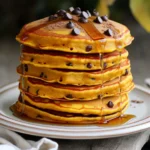 Um köstliche Kürbis Schokoladenstückchen Pfannkuchen zu machen, brauchst du einige einfache Zutaten: - 1 Tasse Weizenmehl (Allzweck) - 1 Esslöffel Backpulver - 1 Teelöffel gemahlener Zimt - 1/2 Teelöffel gemahlene Muskatnuss - 1/4 Teelöffel Salz - 1/2 Tasse Kürbispüree (aus der Dose oder frisch) - 1/2 Tasse Milch (Tier- oder Pflanzenbasiert) - 1 großes Ei - 2 Esslöffel Ahornsirup - 1 Teelöffel Vanilleextrakt - 1/2 Tasse Schokoladenstückchen (halb-süß oder dunkel) - Butter oder Öl zum Braten Diese Zutaten sorgen für einen tollen Geschmack und eine gute Textur. Das Kürbispüree bringt Feuchtigkeit und eine süße Note. Die Schokoladenstückchen sind der leckerste Teil! Einige hilfreiche Dinge für die Zubereitung sind: - Eine große Rührschüssel - Eine separate Schüssel für die feuchten Zutaten - Ein Holzlöffel oder Teigschaber - Eine antihaftbeschichtete Pfanne oder ein Grill - Ein Messbecher für die genauen Mengen Mit diesem Zubehör kannst du den Teig einfach und schnell zubereiten. Falls du spezielle Diäten beachtest, gibt es Anpassungen: - Glutenfrei: Tausche das Weizenmehl gegen eine glutenfreie Mischung aus. - Vegan: Nutze Pflanzenmilch und ersetze das Ei mit einem Leinsamen-Ei (1 Esslöffel Leinsamenmehl mit 2,5 Esslöffel Wasser). - Zuckerfrei: Verwende einen Zuckeraustauschstoff statt Ahornsirup. Diese Alternativen helfen, den Pfannkuchen jedem zugänglich zu machen. Zuerst bereite ich die trockenen Zutaten vor. Ich nehme eine große Schüssel und gebe das Weizenmehl, Backpulver, Zimt, Muskatnuss und Salz hinein. Ich vermenge alles gut mit einem Schneebesen. Es ist wichtig, dass die Zutaten gleichmäßig verteilt sind. So schmecken die Pfannkuchen besser. Jetzt kümmere ich mich um die feuchten Zutaten. Ich nehme eine separate Schüssel. Dort gebe ich das Kürbispüree, die Milch, das Ei, den Ahornsirup und den Vanilleextrakt. Ich rühre alles gut um, bis die Mischung schön glatt ist. Diese Mischung sorgt für den tollen Geschmack der Pfannkuchen. Ich gieße nun die Kürbismischung in die Schüssel mit den trockenen Zutaten. Dann rühre ich vorsichtig mit einem Holzlöffel. Es ist okay, wenn der Teig kleine Klümpchen hat. Zu viel Rühren macht ihn hart. Jetzt füge ich die Schokoladenstückchen hinzu und hebe sie vorsichtig unter. So bleiben die Stückchen ganz und verteilen sich gut im Teig. Ich erhitze eine antihaftbeschichtete Pfanne auf mittlerer Hitze und gebe etwas Butter oder Öl hinein. Dann gieße ich etwa 1/4 Tasse des Teigs in die Pfanne. Ich koche die Pfannkuchen, bis sich Blasen bilden und die Ränder fest aussehen, das dauert etwa 2-3 Minuten. Dann wende ich die Pfannkuchen vorsichtig und brate sie weitere 2 Minuten, bis sie goldbraun sind. Ich nehme sie aus der Pfanne und halte sie warm, während ich den restlichen Teig brate. Um die beste Konsistenz für deinen Pfannkuchenteig zu haben, achte darauf, die trockenen Zutaten gut zu vermischen. Das macht den Teig gleichmäßiger. Wenn du die feuchten Zutaten hinzufügst, mische nur kurz. Kleine Klumpen sind in Ordnung. Überrühren macht die Pfannkuchen zäh. Der Teig sollte dick, aber fließend sein. Die richtige Temperatur ist wichtig. Erhitze deine Pfanne auf mittlere Hitze. Wenn du ein paar Tropfen Wasser in die Pfanne gibst, sollten sie sofort brutzeln. Das zeigt, dass die Pfanne bereit ist. Gieße etwa 1/4 Tasse Teig in die Pfanne und warte, bis sich Blasen bilden. So garen die Pfannkuchen gleichmäßig und werden schön goldbraun. Serviere die Pfannkuchen warm gestapelt auf einem Teller. Träufle etwas warmen Ahornsirup darüber. Für den extra Genuss füge mehr Schokoladenstückchen oben drauf. Eine Prise Zimt macht sie noch aromatischer. Du kannst auch frisches Obst, wie Bananen oder Äpfel, als Beilage verwenden. Diese Kombination bringt eine fruchtige Note in dein Frühstück. {{image_4}} Es gibt viele Wege, deine Kürbis Schokoladenstückchen Pfannkuchen zu variieren. Du kannst Nüsse, wie Walnüsse oder Pekannüsse, hinzufügen. Sie geben einen tollen Crunch. Auch frische Früchte sind eine gute Wahl. Bananen oder Äpfel passen perfekt. Du kannst sie einfach in den Teig mischen oder sie als Topping verwenden. Das bringt Farbe und Geschmack. Jeder hat seinen eigenen Geschmack. Wenn du es würziger magst, füge mehr Zimt oder Muskatnuss hinzu. Für eine süßere Note kannst du mehr Ahornsirup verwenden. Du kannst auch Honig oder Agavensirup ausprobieren. Wenn du experimentierfreudig bist, versuche auch andere Gewürze. Ingwer oder Nelken geben einen interessanten Twist. Es ist einfach, diese Pfannkuchen vegan zu machen. Ersetze das Ei durch eine Banane oder Apfelmus. Du kannst auch Pflanzenmilch verwenden. Für glutenfreie Pfannkuchen nutze glutenfreies Mehl. Viele Marken bieten gute Alternativen an. Achte darauf, dass alle Zutaten glutenfrei sind. So kannst du jeden glücklich machen, ohne den Geschmack zu verlieren. Um die übrig gebliebenen Pfannkuchen frisch zu halten, lege sie auf einen Teller. Decke sie mit Frischhaltefolie oder einem sauberen Küchentuch ab. So bleibt die Feuchtigkeit drin. Du kannst die Pfannkuchen auch in einen luftdichten Behälter legen. Achte darauf, dass sie abgekühlt sind, bevor du sie lagerst. Für den besten Geschmack empfehle ich, die Pfannkuchen in einer Pfanne aufzuwärmen. Erhitze sie bei mittlerer Hitze. Wende sie nach ein oder zwei Minuten. Dadurch werden sie warm und knusprig. Alternativ kannst du die Pfannkuchen auch im Toaster aufwärmen. Das funktioniert gut und spart Zeit. Im Kühlschrank halten sich die Pfannkuchen etwa drei bis fünf Tage. Stelle sicher, dass sie gut verpackt sind, um Gerüche zu vermeiden. Wenn du sie länger aufbewahren möchtest, friere sie ein. Lege die Pfannkuchen in Gefrierbeutel und schiebe die Luft heraus. So bleiben sie bis zu drei Monate frisch. Wenn du sie auftauen möchtest, lasse sie einfach im Kühlschrank über Nacht. Um die Pfannkuchen fluffiger zu machen, kannst du mehr Backpulver verwenden. Erhöhe es auf 1,5 Esslöffel. Dies hilft, die Luftigkeit zu steigern. Ein weiterer Trick ist, das Eiweiß vom Eigelb zu trennen. Schlage das Eiweiß steif und hebe es vorsichtig unter den Teig. So bekommst du eine leichtere Textur. Ja, du kannst das Kürbispüree selbst machen. Koche einen kleinen Kürbis bis er weich ist. Lass ihn abkühlen und püriere ihn in einem Mixer. Frisches Kürbispüree hat einen tollen Geschmack und ist einfach zuzubereiten. Es ist eine gesunde Option und voller Nährstoffe. Die besten Beilagen für diese Pfannkuchen sind frisches Obst und Joghurt. Auch Nüsse oder Sahne passen sehr gut. Ein Spritzer Ahornsirup macht alles süßer. Du kannst auch Zimt oder Puderzucker darüber streuen. Diese Beilagen sorgen für mehr Geschmack und Textur. Du kannst die Pfannkuchen bis zu drei Tage im Kühlschrank aufbewahren. Lagere sie in einem luftdichten Behälter. Wenn du sie länger aufbewahren willst, friere sie ein. Die Pfannkuchen halten sich bis zu zwei Monate im Gefrierfach. Erwärme sie einfach in der Mikrowelle oder in einer Pfanne. Kürbis-Schokoladenstückchen-Pfannkuchen sind ein köstliches und flexibles Gericht. Wir haben die Hauptzutaten und mögliche Optionen erkundet, von der Zubereitung bis zu den perfekten Bratmethoden. Mit einfachen Tipps erreichst du die ideale Konsistenz und die besten Serviervorschläge. Variationen machen die Pfannkuchen anpassbar für jeden Geschmack. Verwende unsere Lagerungshinweise, um Reste frisch zu halten. Egal, ob du glutenfrei oder vegan kochen willst, diese Pfannkuchen bieten dir viele Möglichkeiten. Probiere sie aus und genieße jeden Bissen!