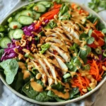 Für den Thai Erdnuss-Hühnchen-Salat benötigen Sie folgende Zutaten: - 2 gegrillte Hühnerbrustfilets, in Scheiben geschnitten - 4 Tassen gemischte Blattsalate (Spinat, Rucola und Romanasalat) - 1 Tasse geraspelte Karotten - 1 rote Paprika, dünn geschnitten - 1 Tasse Gurke, dünn geschnitten - ½ Tasse rote Kohl, geraspelt - ¼ Tasse frischer Koriander, gehackt - ¼ Tasse Frühlingszwiebeln, in Ringe geschnitten - ½ Tasse geröstete, ungesalzene Erdnüsse, grob gehackt Für das Erdnuss-Dressing brauchen Sie: - ¼ Tasse cremige Erdnussbutter - 2 Esslöffel Sojasauce (oder Tamari für glutenfrei) - 2 Esslöffel Limettensaft - 1 Esslöffel Honig oder Ahornsirup - 1 Teelöffel Sesamöl - 1-2 Esslöffel Wasser (um das Dressing nach Bedarf zu verdünnen) - Erdnussbutter: Wählen Sie eine cremige Sorte. Sie gibt dem Dressing eine glatte Konsistenz. Bio-Optionen sind oft besser im Geschmack. - Sojasauce: Verwenden Sie Tamari, wenn Sie glutenfrei essen möchten. Der Geschmack bleibt gleich. - Limettensaft: Frisch gepresster Saft gibt mehr Aroma. Vermeiden Sie Flaschenlimettensaft, wenn möglich. - Koriander: Dieser frische Kräuter bringt einen tollen Geschmack. Achten Sie darauf, ihn gut zu hacken. - Hühnchen: Bietet hochwertiges Protein. Gut für Muskeln und Sättigung. - Gemischte Blattsalate: Voll von Vitaminen und Ballaststoffen. Fördert die Verdauung und gibt Energie. - Karotten: Reich an Beta-Carotin, gut für die Augen. - Paprika: Enthält viel Vitamin C. Unterstützt das Immunsystem. - Erdnüsse: Eine gute Quelle für gesunde Fette und Protein. Sie helfen, den Cholesterinspiegel zu senken. - Koriander und Frühlingszwiebeln: Diese Kräuter bringen zusätzliche Nährstoffe und Geschmack. Zuerst machen wir das Erdnuss-Dressing. Nimm eine mittelgroße Schüssel. Füge die Erdnussbutter, Sojasauce, Limettensaft, Honig und Sesamöl hinzu. Benutze einen Schneebesen, um alles gut zu vermischen. Achte darauf, dass die Mischung glatt wird. Wenn das Dressing zu dick ist, gebe nach und nach Wasser hinzu. Rühre weiter, bis die gewünschte Konsistenz erreicht ist. Stelle das Dressing dann beiseite. Nun bereiten wir die Salatbasis vor. Nimm eine große Salatschüssel. Lege die gemischten Blattsalate als erste Schicht hinein. Du kannst Spinat, Rucola und Romanasalat verwenden. Danach fügst du die geraspelten Karotten, die dünn geschnittene Paprika und die Gurke hinzu. Schließlich kommt der rote Kohl in die Schüssel. Diese bunten Zutaten machen deinen Salat frisch und knackig. Jetzt kommt der wichtigste Teil: das Hühnchen. Nimm die gegrillten Hühnerbrustfilets und schneide sie in Scheiben. Verteile die Hähnchenstücke gleichmäßig über der Salatbasis. Als Nächstes streue den gehackten Koriander und die geschnittenen Frühlingszwiebeln darüber. Zum Schluss fügst du die grob gehackten Erdnüsse hinzu. Diese geben dem Salat einen tollen Crunch und viel Geschmack. Kurz bevor du den Salat servierst, träufle das Erdnuss-Dressing über die Zutaten in der Schüssel. Mische alles vorsichtig, damit sich das Dressing gut verteilt. Probiere den Salat und passe den Geschmack an. Vielleicht brauchst du mehr Salz oder Limettensaft. Serviere den Salat in tiefen Tellern. Garniere ihn mit weiteren Erdnüssen und Koriander für eine schöne Optik. Viel Spaß beim Genießen! Um das Dressing perfekt zu machen, starte mit der Erdnussbutter. Wähle eine cremige Sorte. Füge dann die Sojasauce, den Limettensaft und den Honig hinzu. Rühre alles gut um. Das Wasser ist der Schlüssel. Du kannst 1 bis 2 Esslöffel Wasser hinzufügen, um die Dicke zu steuern. Wenn das Dressing zu dick ist, gib mehr Wasser hinzu. Achte darauf, dass es schön glatt und leicht fließend ist. So haftet es gut an deinem Salat. Das Rezept ist sehr flexibel. Du kannst das Gemüse nach deinem Geschmack ändern. Möchtest du mehr Farbe? Füge violette Karotten oder gelbe Paprika hinzu. Wenn du es scharf magst, probiere etwas Chili oder frischen Ingwer. Bei den Erdnüssen kannst du auch Mandeln oder Cashews verwenden. Für eine vegane Variante, ersetze den Honig durch Ahornsirup. So bleibt der Salat lecker und passt deinen Vorlieben an. Ein häufiger Fehler ist, das Dressing zu früh hinzuzufügen. Warte bis kurz vor dem Servieren. So bleibt der Salat frisch und knackig. Achte auch auf die Menge der Zutaten. Zu viel Dressing kann den Salat matschig machen. Eine andere Falle ist, das Gemüse nicht gut zu waschen. Schmutz oder Pestizide können den Genuss stören. Wasche alles gründlich, bevor du anfängst. So erhältst du den besten Geschmack und die beste Qualität. {{image_4}} Wenn Sie eine vegetarische oder vegane Version des Thai Erdnuss-Hühnchen-Salats machen möchten, gibt es großartige Optionen. Statt Hühnchen können Sie Tofu verwenden. Tofu liefert viel Protein und nimmt den Geschmack des Dressings gut auf. Sie können ihn würfeln und anbraten oder einfach roh verwenden. Ein weiterer Ersatz ist Tempeh. Tempeh hat einen nussigen Geschmack und passt gut zum Salat. Marinieren Sie es in Sojasauce, bevor Sie es anbraten. Für Abwechslung können Sie auch andere Proteinquellen nutzen. Gegrillte Garnelen bringen einen frischen Geschmack. Sie sind schnell zubereitet und passen gut zu den anderen Zutaten. Kochschinken oder gebratene Hähnchenbrust sind ebenfalls gute Optionen. Diese Variationen machen den Salat spannend und lecker. Die Auswahl an Gemüse und Obst ist riesig. Sie können Paprika durch Avocado ersetzen, um eine cremige Textur zu erhalten. Zusätzlich können Sie Erbsen oder Edamame für einen zusätzlichen Crunch hinzufügen. Diese sind reich an Ballaststoffen und geben Farbe. Frisches Obst wie Mango oder Ananas bringt eine süße Note. Diese Kombinationen machen den Salat noch aufregender und gesünder. Um den Thai Erdnuss-Hühnchen-Salat frisch zu halten, lege ihn in einen luftdichten Behälter. Achte darauf, dass der Salat nicht zu lange bei Raumtemperatur bleibt. Stelle den Behälter in den Kühlschrank, wenn du den Salat nicht sofort isst. So bleibt er knackig und lecker. Das Dressing solltest du separat aufbewahren. Fülle es in ein kleines Glas oder eine Flasche mit Deckel. So bleibt es frisch und die Aromen verändern sich nicht. Vor dem Servieren schüttle das Dressing gut, um alles zu vermischen. Der Salat hält sich im Kühlschrank etwa 2-3 Tage. Du kannst die Reste auch für Wraps oder Sandwiches verwenden. Das gibt dir eine tolle neue Mahlzeit. Wenn das Dressing nicht verbraucht wird, ist es etwa eine Woche haltbar. Nutze es für andere Salate oder als Dip. Du kannst das Dressing leicht anpassen. Wenn du es schärfer magst, füge etwas Chiliflocken hinzu. Für mehr Süße kannst du mehr Honig oder Ahornsirup verwenden. Wenn du eine cremigere Textur möchtest, nimm mehr Erdnussbutter. Magst du es dünner? Füge einfach mehr Wasser hinzu. Sei kreativ und passe es deinem Geschmack an! Ja, dieser Salat eignet sich gut für Meal Prepping. Du kannst die Zutaten gut getrennt aufbewahren. Halte das Dressing separat, damit der Salat frisch bleibt. Wenn du bereit bist zu essen, mische einfach alles zusammen. So bleibt der Salat knackig und lecker. Du kannst viele Beilagen wählen. Gegrilltes Gemüse passt gut. Reis oder Quinoa sind auch tolle Optionen. Ein einfaches Brot oder Fladenbrot ergänzt den Salat gut. Experimentiere und finde deine perfekten Kombinationen für ein tolles Essen. Ja, du kannst gefrorenes Hühnchen verwenden. Achte darauf, es vorher gut zu kochen. Das Hühnchen sollte ganz durchgegart sein, bevor du es in den Salat gibst. So bleibt der Salat frisch und lecker. Denke daran, das Hühnchen rechtzeitig aufzutauen. Der Blogbeitrag bietet eine einfache Anleitung für einen leckeren Salat mit Erdnuss-Dressing. Wir haben die Zutaten aufgelistet, deren Nährwert erklärt und hilfreiche Tipps gegeben. Außerdem kannst du das Rezept nach deinen Wünschen anpassen und Variationen ausprobieren. Achte auf die Lagerung, um Frische zu garantieren. Nutze diese Informationen, um schmackhafte Salate zu kreieren. Viel Spaß beim Ausprobieren!