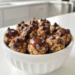 Die Hauptzutaten sind einfach und gesund. Hier ist, was du brauchst: - 1 Tasse Haferflocken - 1/2 Tasse natürliche Erdnussbutter - 1/4 Tasse Honig oder Ahornsirup - 1/4 Tasse Schokoladen-Proteinpulver - 1/4 Tasse Mini-Schokoladenstückchen - 1/4 Tasse gemahlene Leinsamen - Eine Prise Salz - Optional: 1/2 Teelöffel Vanilleextrakt Diese Zutaten geben den Bällchen ihren tollen Geschmack und die nötige Energie. Die Haferflocken sorgen für Ballaststoffe. Die Erdnussbutter liefert gesunde Fette und einen nussigen Geschmack. Das Proteinpulver hilft, die Bällchen proteinreich zu machen. Du kannst Honig oder Ahornsirup verwenden. Honig hat einen süßen, blumigen Geschmack. Er wird oft als natürlicher Süßstoff genutzt. Ahornsirup hat einen tiefen, kräftigen Geschmack. Er passt gut zu den Nüssen. Beide sind gesund, aber Honig ist süßer. Wenn du vegan bist, wähle Ahornsirup. Er ist eine großartige Alternative. Beide Süßstoffe machen die Bällchen klebrig und lecker. Du kannst auch mit der Menge spielen, um die Süße anzupassen. Gemahlene Leinsamen sind toll für die Gesundheit. Sie sind reich an Ballaststoffen, Omega-3-Fettsäuren und Antioxidantien. Diese Nährstoffe helfen, das Herz gesund zu halten. Außerdem fördern sie die Verdauung. Die Leinsamen geben den Bällchen eine angenehme Textur. Sie machen die Bällchen nahrhaft und sättigend. Wenn du sie hinzufügst, erhältst du eine Portion gesunder Fette. Das macht die Bällchen perfekt für einen Snack nach dem Sport oder einfach für zwischendurch. Zuerst nehmen Sie eine große Rührschüssel. Geben Sie die Haferflocken, das Schokoladen-Proteinpulver, die gemahlenen Leinsamen und eine Prise Salz hinein. Mischen Sie diese trockenen Zutaten gut. Achten Sie darauf, dass alles gleichmäßig verteilt ist. Dies ist wichtig, damit jeder Biss gleich lecker schmeckt. In einer separaten Schüssel verrühren Sie die Erdnussbutter und den Honig oder Ahornsirup. Wenn Sie möchten, fügen Sie auch den Vanilleextrakt hinzu. Rühren Sie alles, bis die Mischung schön glatt ist. Diese feuchte Mischung sorgt für den tollen Geschmack der Bällchen. Jetzt gießen Sie die feuchte Mischung zu den trockenen Zutaten. Rühren Sie alles gut um, bis alles zusammenkommt. Wenn der Teig zu dick ist, können Sie etwas Wasser oder mehr Honig hinzufügen. Nachdem alles gut vermischt ist, heben Sie die Mini-Schokoladenstückchen vorsichtig unter. Formen Sie dann kleine Bällchen mit Ihren Händen. Diese sollten etwa 2,5 cm groß sein. Legen Sie die Bällchen auf ein Backblech oder einen Teller. Kühlen Sie sie für mindestens 30 Minuten im Kühlschrank. So werden sie fest und lecker. Bewahren Sie die Bällchen in einem luftdichten Behälter im Kühlschrank auf. Dort halten sie sich bis zu einer Woche. Um die perfekte Konsistenz für deine Schokoladen-Erdnussbutter-Protein-Bällchen zu erreichen, ist das Mischungsverhältnis wichtig. Wenn der Teig zu trocken ist, füge einen Spritzer Wasser hinzu. Ist er zu nass, gib etwas mehr Haferflocken dazu. Achte darauf, dass die Mischung gut zusammenhält, aber nicht klebrig ist. Eine gute Konsistenz erleichtert das Formen der Bällchen. Um die Bällchen frisch zu halten, lagere sie in einem luftdichten Behälter. Stelle sicher, dass der Behälter gut verschlossen ist. Im Kühlschrank halten sie bis zu einer Woche. Für längere Haltbarkeit kannst du die Bällchen auch einfrieren. Lege sie einfach in einen Gefrierbeutel und entnehme nur, was du brauchst. Für besondere Anlässe kannst du die Bällchen kreativ anrichten. Lege sie in eine schöne Schüssel und streue einige Mini-Schokoladenstückchen darüber. Das sieht nicht nur toll aus, sondern macht die Bällchen auch noch verlockender. Eine weitere Idee ist, sie in Pergamentpapier zu wickeln. So hast du einen handlichen Snack für unterwegs. {{image_4}} Sie können die Schokoladen-Erdnussbutter-Protein-Bällchen ganz leicht variieren. Fügen Sie Nüsse oder Trockenfrüchte hinzu. Mandeln, Walnüsse oder Cashewkerne passen gut. Sie bringen einen knackigen Biss und gesunde Fette. Trockenfrüchte wie Rosinen oder Cranberries sorgen für Süße. Mischen Sie einfach eine halbe Tasse Ihrer Wahl in den Teig. Achten Sie darauf, die Menge der anderen Zutaten anzupassen, um die Konsistenz zu halten. Wenn Sie weniger Zucker möchten, ist das auch möglich. Verwenden Sie anstelle von Honig oder Ahornsirup einen reifen Banane. Die Banane macht die Bällchen süß und weich. Sie können auch Stevia oder Erythrit verwenden, wenn Sie einen kalorienarmen Süßstoff suchen. Mischen Sie diese Alternativen gut mit der Erdnussbutter. So bleibt der Geschmack lecker und der Zuckergehalt niedrig. Für vegane Protein-Bällchen lassen sich Eier und Honig leicht ersetzen. Anstelle von Honig verwenden Sie Agavendicksaft oder Dattelsirup. Beide sind süß und pflanzlich. Für die Bindung können Sie Leinsamen oder Chiasamen verwenden. Mischen Sie einen Esslöffel gemahlene Leinsamen mit drei Esslöffeln Wasser. Lassen Sie es fünf Minuten stehen, bis es dick wird. So erhalten Sie eine tolle Konsistenz für die Bällchen. Die Schokoladen-Erdnussbutter-Protein-Bällchen brauchen etwas Zeit zum Kühlen. Nach der Zubereitung stelle ich sie für mindestens 30 Minuten in den Kühlschrank. So werden sie fest. Im Kühlschrank halten sie sich bis zu einer Woche. Ich achte darauf, sie schnell zu essen, weil sie frisch am besten schmecken. Ich bewahre die Proteinbällchen in einem luftdichten Behälter auf. So bleiben sie frisch und lecker. Ein guter Behälter schützt die Bällchen vor Luft und Feuchtigkeit. Ich empfehle, die Bällchen nicht zu lange offen zu lassen. Das kann ihren Geschmack ändern. Wenn ich die Bällchen länger aufbewahren möchte, friere ich sie ein. Ich lege sie zuerst auf ein Backblech und friere sie für ein paar Stunden ein. Dann packe ich sie in einen gefrierfesten Beutel. So halten sie sich bis zu drei Monate. Vor dem Essen lasse ich sie einfach kurz stehen. Sie werden schnell wieder weich und sind dann bereit zum Genießen! Die Schokoladen-Erdnussbutter-Protein-Bällchen haben etwa 100 Kalorien pro Bällchen. Diese Zahl kann leicht schwanken. Die genauen Kalorien hängen von den genauen Zutaten ab. Zum Beispiel, wenn Sie mehr Honig oder Schokoladenstückchen verwenden, steigt die Kalorienzahl. Wenn Sie die Bällchen aufteilen, können Sie die Kalorien pro Portion einfach berechnen. Ja, Sie können diese Bällchen ohne Proteinpulver machen. Wenn Sie kein Proteinpulver haben, nehmen Sie einfach mehr Haferflocken. Sie können auch gemahlene Nüsse oder mehr Leinsamen verwenden. Das gibt den Bällchen einen ähnlichen Geschmack und die Textur bleibt gut. Achten Sie darauf, die anderen Zutaten leicht anzupassen, damit die Bällchen gut zusammenhalten. Die Bällchen halten bis zu einer Woche im Kühlschrank. Bewahren Sie sie in einem luftdichten Behälter auf. So bleiben sie frisch und lecker. Wenn Sie sie länger aufbewahren möchten, können Sie sie auch einfrieren. Dann bleiben sie für mehrere Monate haltbar. Vor dem Essen lassen Sie sie einfach etwas auftauen. Die Schokoladen-Erdnussbutter-Protein-Bällchen sind einfach zuzubereiten und lecker. Wir haben die wichtigen Zutaten besprochen, von der Auswahl zwischen Honig und Ahornsirup bis zu den Vorteilen von Leinsamen. In der Schritt-für-Schritt-Anleitung sahen wir, wie man die Konsistenz perfekt hinbekommt. Zudem gibt es viele Variationen und Tipps zur Lagerung. Diese Bällchen sind nicht nur nahrhaft, sondern auch vielseitig und anpassbar. Probier sie aus und finde deine Lieblingsversion!